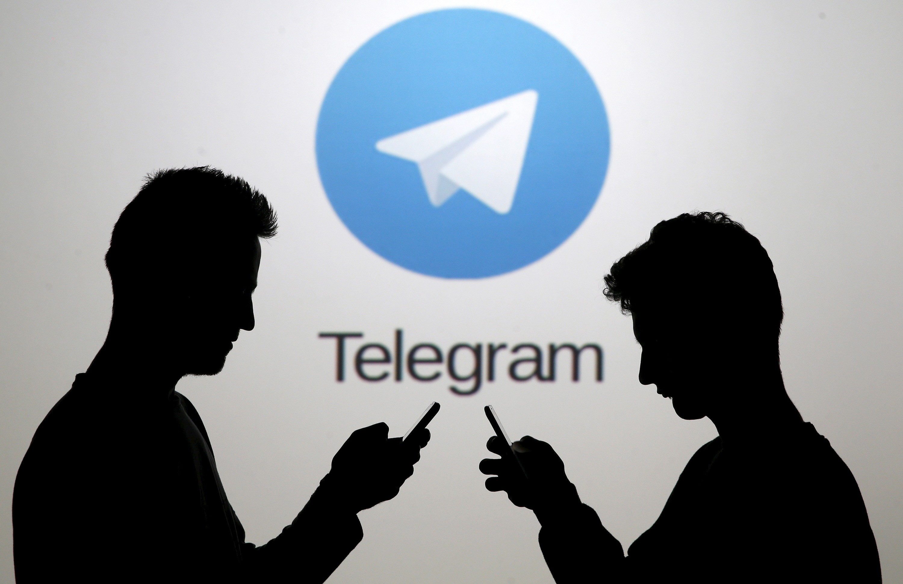 Two men pose with smartphones in front of a screen showing the Telegram logo in this picture illustration taken in Zenica, Bosnia and Herzegovina November 18, 2015. The mobile messaging service Telegram, created by the exiled founder of Russia's most popular social network site, has emerged as an important new promotional and recruitment platform for Islamic State. The service, set up two years ago, has caught on in many corners of the globe as an ultra-secure way to quickly upload and share videos, texts and voice messages. It counts 60 million active users around the world. Picture taken November 18. REUTERS/Dado Ruvic - RTS7W3T